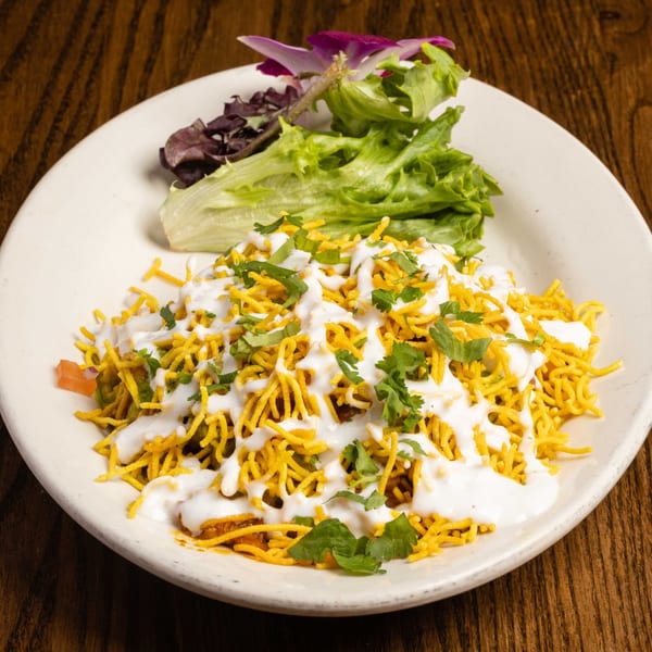 Indian Bhel Puri with crispy noodles, yogurt sauce, cilantro, and a side salad.