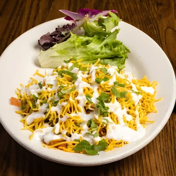 Indian chaat with crispy noodles, yogurt, and cilantro, served with a side salad.