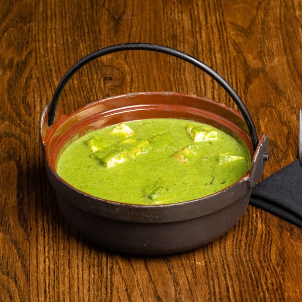 Palak Paneer, a vibrant green Indian dish with paneer cheese, served in a rustic pot.